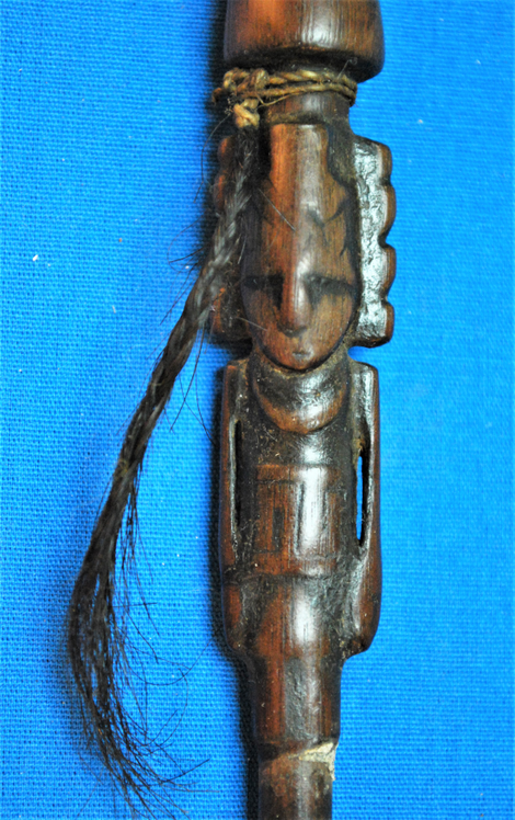 A carved human-like figure on the wooden snuffing tube.